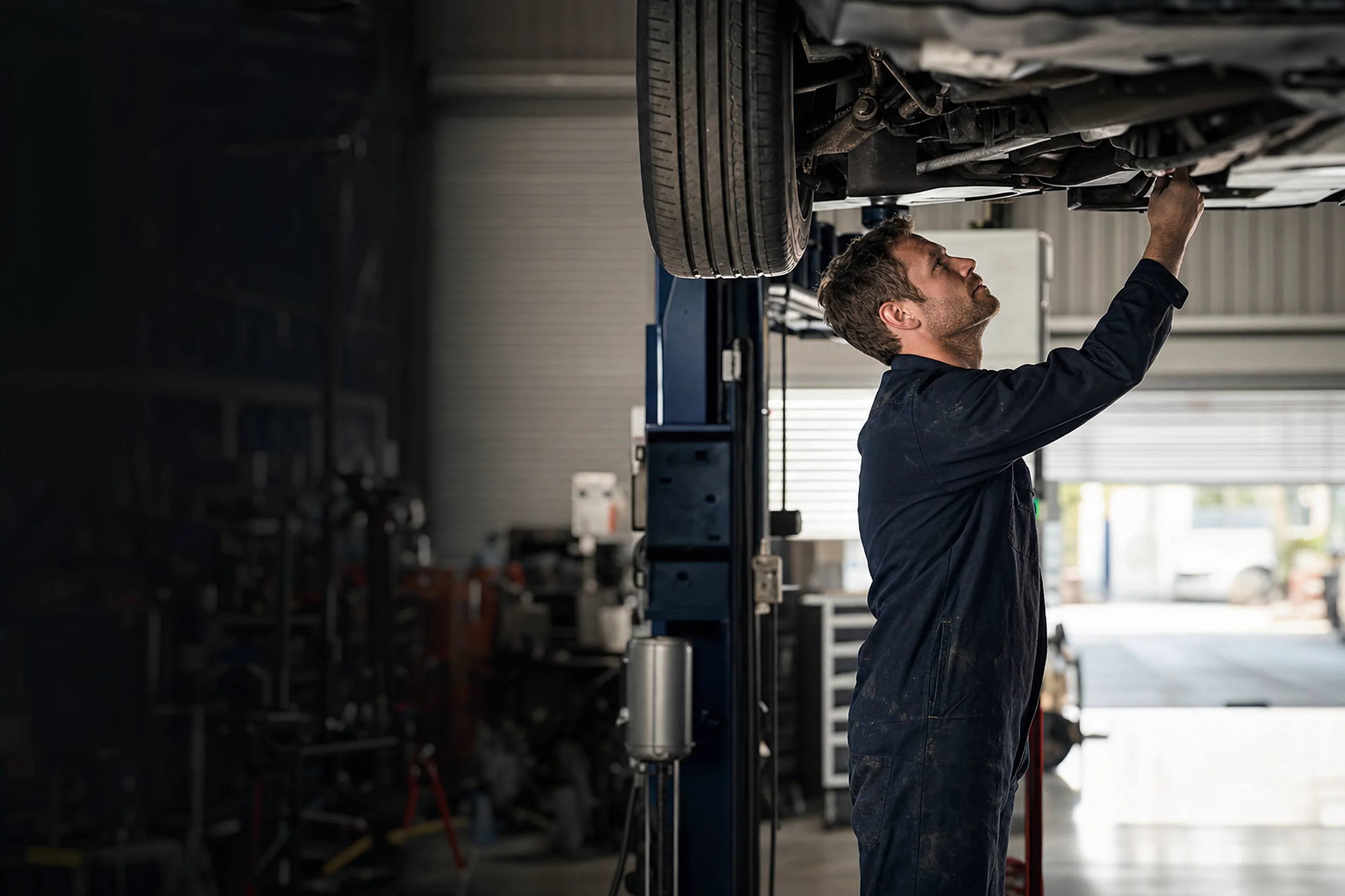 Mechanic working under the bonnet of a car in an Australian workshop